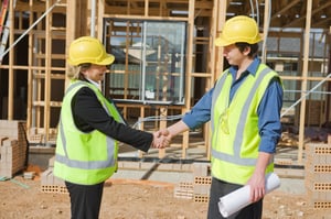 A man and woman at a construction site shake hands