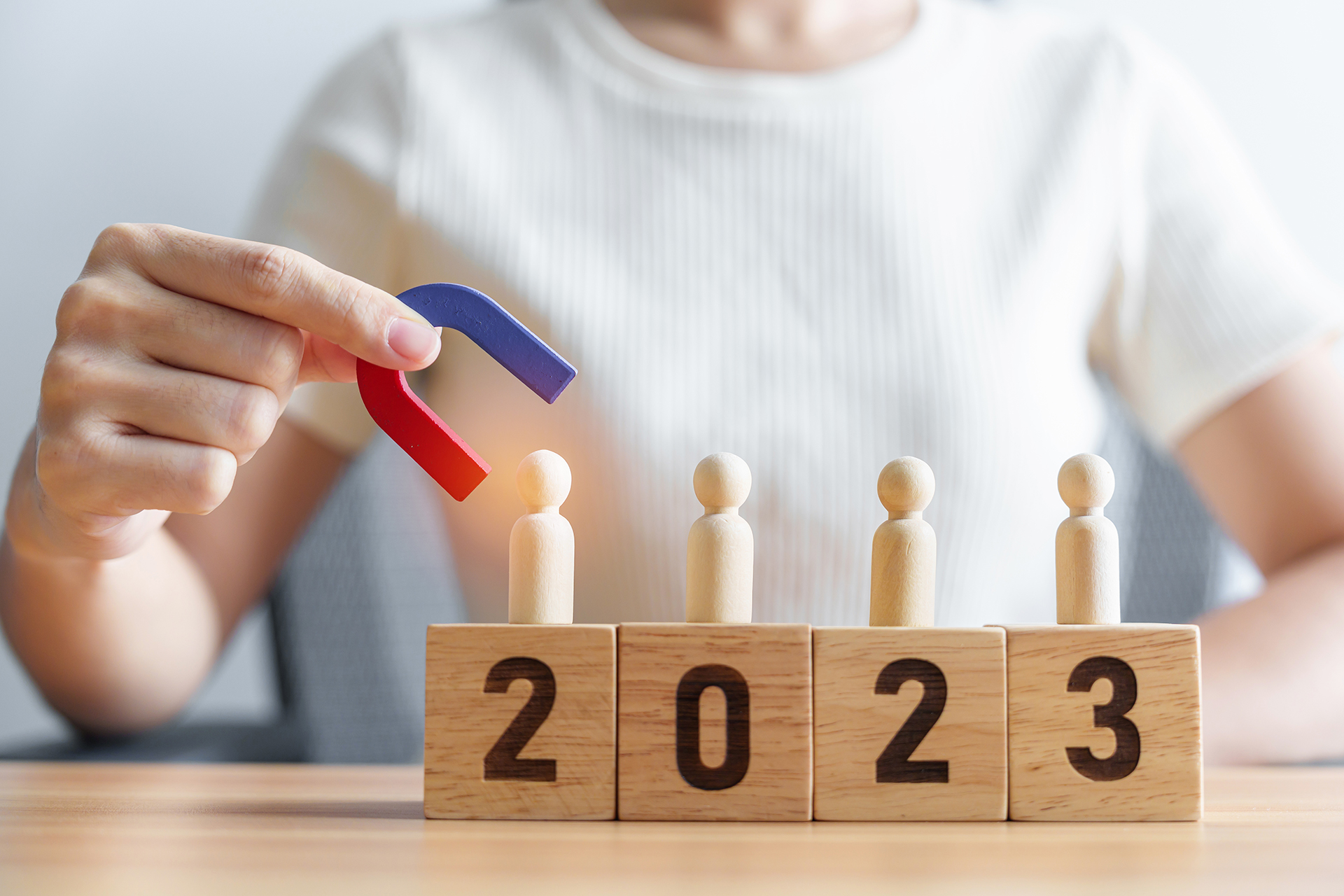 hand holding magnet and pulling man wooden figure from the crowd employee with 2023 Year block. Human resource management, Recruitment, Teamwork, strategy, toxic people and leadership Concepts 